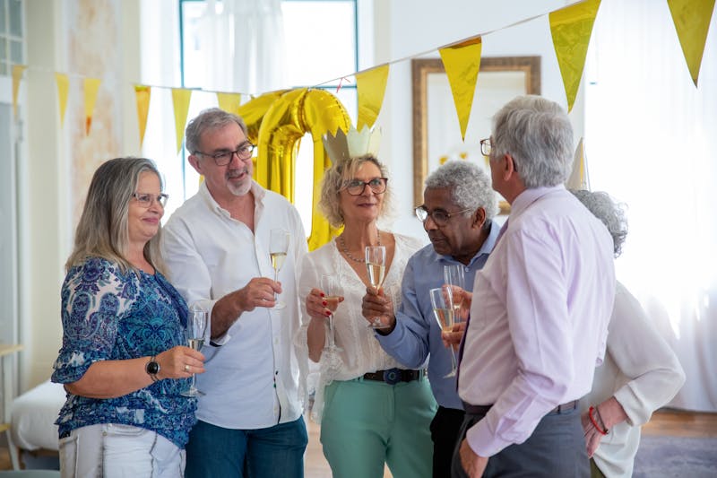 Seniors enjoying a happy gathering together in a community that reflects how much does it cost to live in a senior living facility
