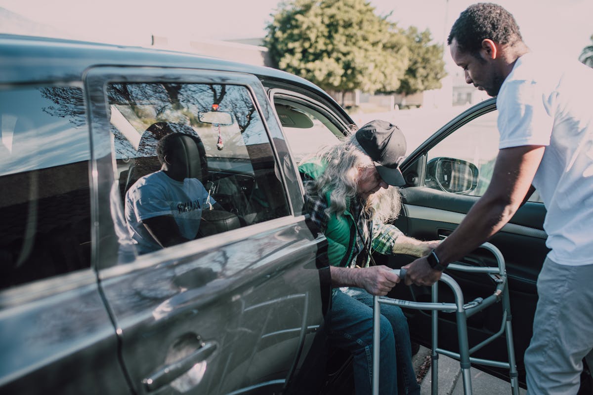 Senior transportation services helping an older adult safely get into a car with mobility support