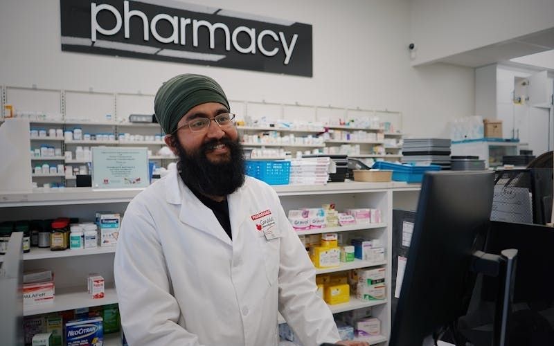Pharmacist reviewing a prescription to confirm is goodrx legit for a customer at the pharmacy counter